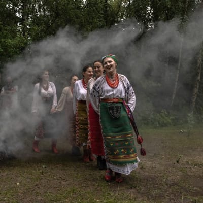 Ukrainska kvinnor i folkdräkt firar högtiden Ivana Kupala dansande runt en rykande brasa.