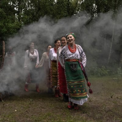 Ukrainska kvinnor i folkdräkt firar högtiden Ivana Kupala dansande runt en rykande brasa.