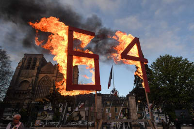 En ställning med med en brinnande text med siffrorna"64"under en demonstration.