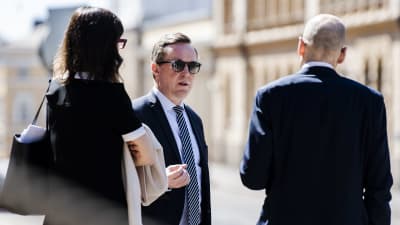 Mika Lintilä står och pratar med två andra personer som har ryggen mot kameran utanför Ständerhuset i Helsingfors.