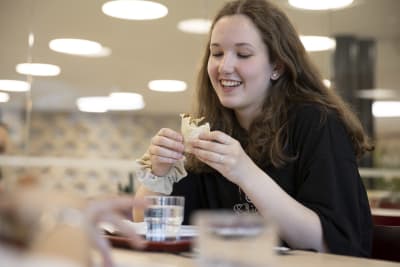 Kvinnlig skolelev äter skollunch, en vegetarisk tortilla.