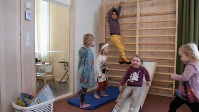 Barn klättar på en ribbstol och åker rutschkana i ett daghem.