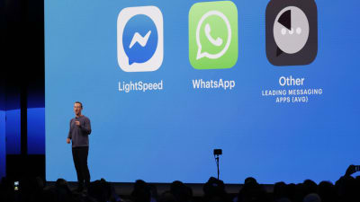 Mark Zuckerberg håller ett föredrag framför en blå bakgrund med några appsymboler som projiceras. 