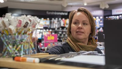 En kvinna tittar över en hylla med pennor i en bokhandel.