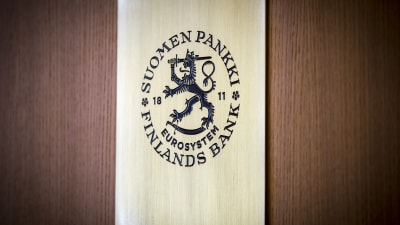 Finlands Banks logo mot en trävägg.