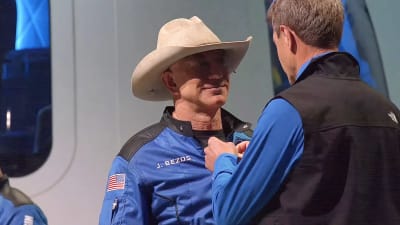 Jeff Bezos får ett astronautmärke fäst på kragen.