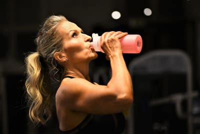 Fitnessidrottaren Agneta Honkala dricker vatten under gymträning.
