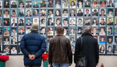 Tre män betraktar en vägg av porträtt av offer efter attacken mot Dubrovka-teatern 2002. 