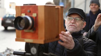 En man tar med en gammal kamera ett nytt fotografi på samma ställe där Finlands första fotografi tog sår 1842.