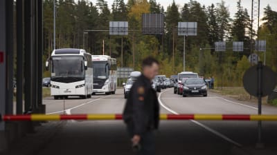 I förgrunden en vakt vid gränsen mellan Finland och Ryssland, i bakgrunden bilar.