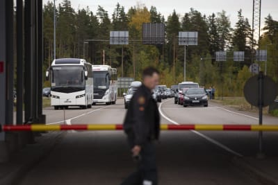 I förgrunden en vakt vid gränsen mellan Finland och Ryssland, i bakgrunden bilar.