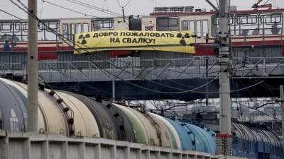 En spårvagn och en gul banner med texten "välkommen till skräpdumpen" på ryska.