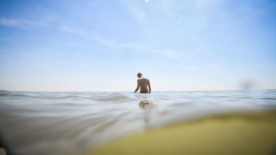 En man simmar i havet en varm sommardag i Frankrike.