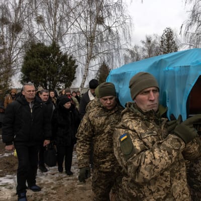 Soldater bär på en likkista täckt med en ukrainsk flagga.