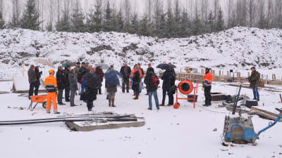 Många personer står ute i snöyra för att mura en grundsten