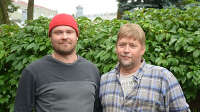 Jarno Sula och Petri Vahteri står utomhus framför en grön häck och tittar in i kameran.