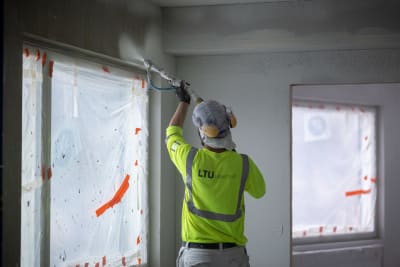 En byggare sprutmålar en vägg.
