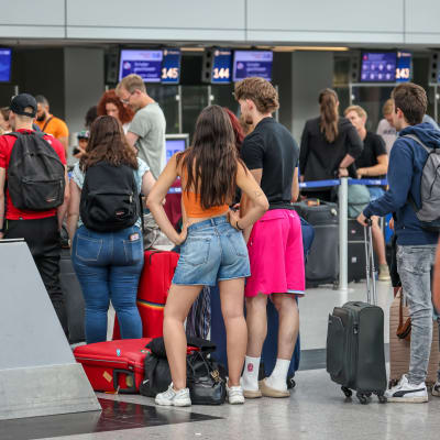 Personer står i kö på en flygplats.