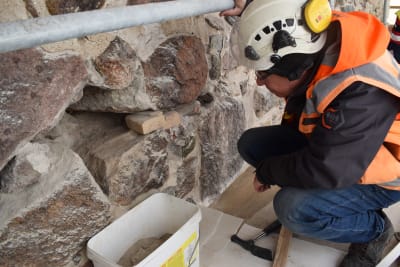 Arkeologi Kari Uotila katsoo muurissa oleva aaukkoa.