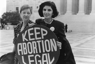 Två kvinnor bakom en skylt med texten "keep abortion legal"