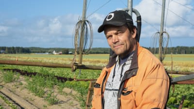 Jordbrukaren Christer Finne står på ett fält framför en bevattningsanläggning.