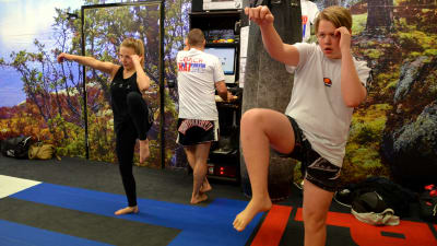 En kvinna och en man som tränar thaiboxning.