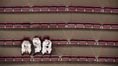 Tre personer sitter på en annars tom läktare under VM tävlingarna i Doha 2019. 