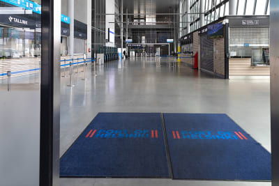 Dörrarna öppnas till en tom färjeterminal med två stora blå mattor på golvet, där det står Port of Helsinki.