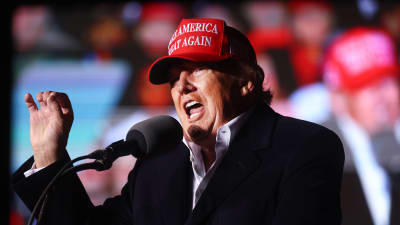 USA:s tidigare president Donald Trump talar i mikrofon på ett kampanjevenemang i Arizona. Han har på sig sin röda keps med texten "Make America great again". 