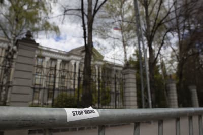 På ett metallstaket framför Rysslands ambassad, en stor klassisk byggnad omgiven av träd, finns ett klistermärke med texten Stop War.