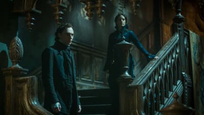 Tom Hiddleston och Jessica Chastain står i bred trappa i skräckens boning.