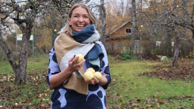 Elise Hindström under äppelträd med äpplen i händerna.