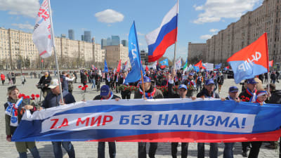 Ett antal ryska personer håller upp en flagga där det står "En värld utan nazism". 