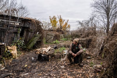 En soldat vilar vid ett förfallet och krigsskadat hus i Luhansk län i november 2022.