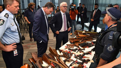 Justitieminister Michael Keenan och premiärminister Malcolm Turnbull ser på en del av de över 50 000 vapen som polisen samlade in