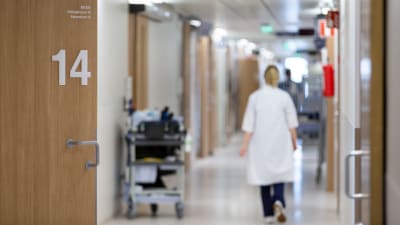 En sjukskötare går genom sjukhuskorridor.
