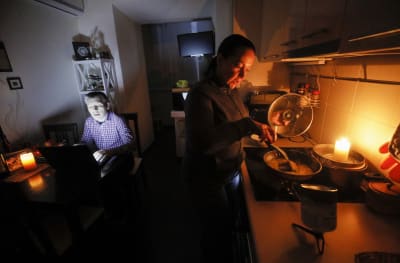 En kvinna lagar man på ett friluftskök som riggats ovanpå spisen i familjens kök.