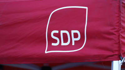 Socialdemokratiska partiets logotyp i vitt på en röd tältduk.