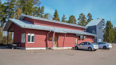 Rött trähus med två bilar parkerade framför sig.