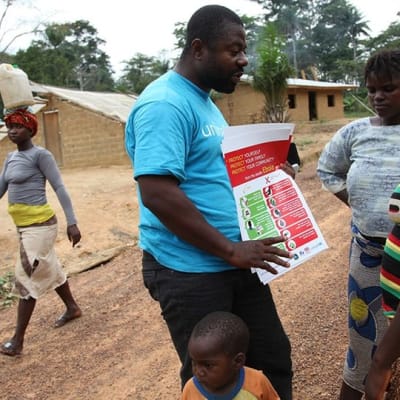 En FN-anställd berättar för några invånare i Liberia hur man undviker ebola.