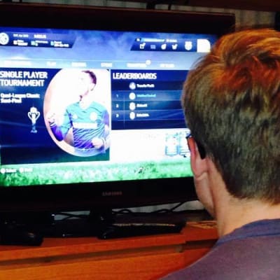 En pojke spelar FIFA 15 på datorn.