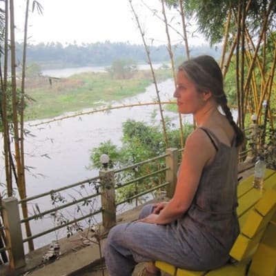 Janna Thorström sitter på en bänk och tittar ut över en flod i Indien.