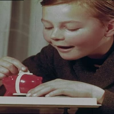 Poika laittaa rahaa säästöpossuun. Kuva 60-luvulta.