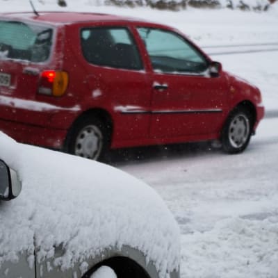 Auto lumen peitossa ja taustalla auto lumipyryssä.