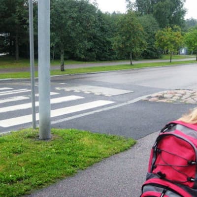 Ekaluokkalainen valmistautuu ylittämään tien suojatietä pitkin matkalla kouluun.