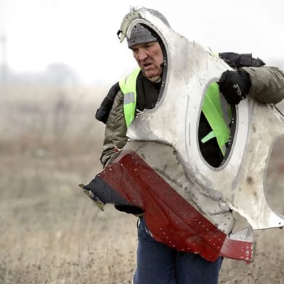 Työntekijä kantaai tuhotun malesialaiskoneen palaa Grabovon kylässä Ukrainassa