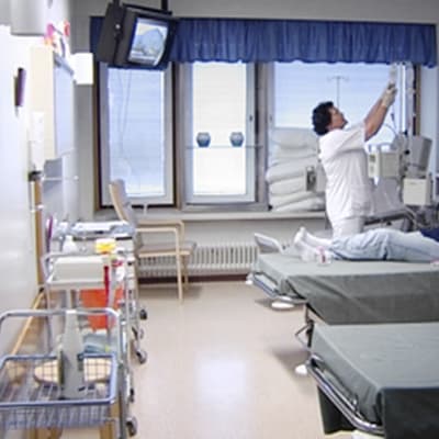 Sairaanhoitaja vaihtaa potilaan tiputuspussia sairaalahuoneessa.