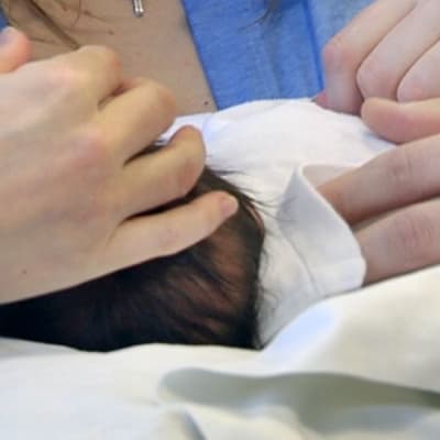Vanhemmat silittävät vauvaa sairaalan synnytysosastolla.
