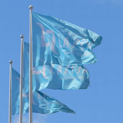 Lappian liput liehuvat tuulessa vaaleansinistä taivasta vasten.