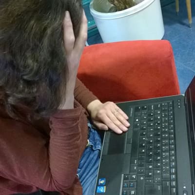 Kuvassa  nainen katsoo kannettavan tietokoneen mustaa ruutua.